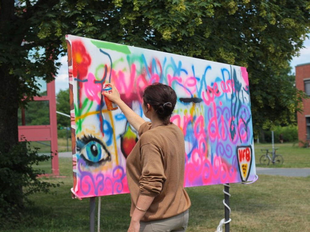 Frau sprayt Graffiti auf eine Leinwand