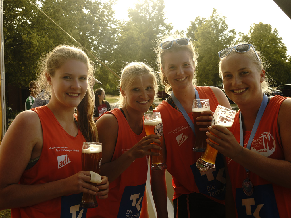 Vier Beachvolleyballerinnen feiern ihren Turniersieg mit einem Glas Weißbier