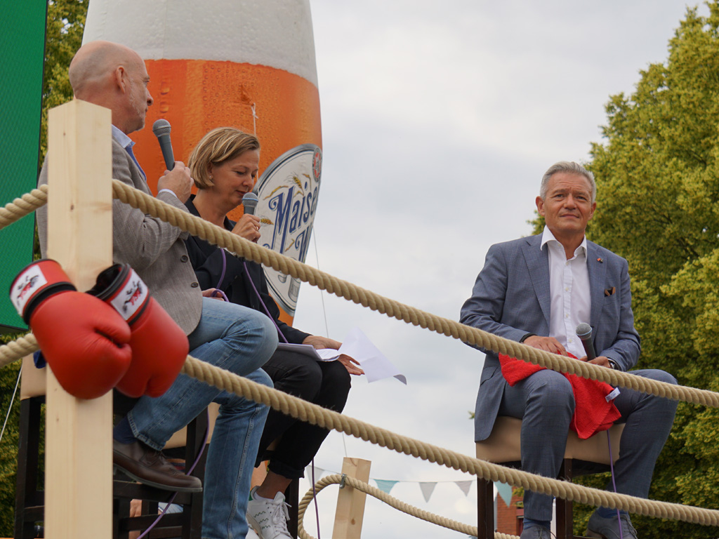 Zwei Männer und eine Frau diskutieren bei einer Podiumsdiskussion