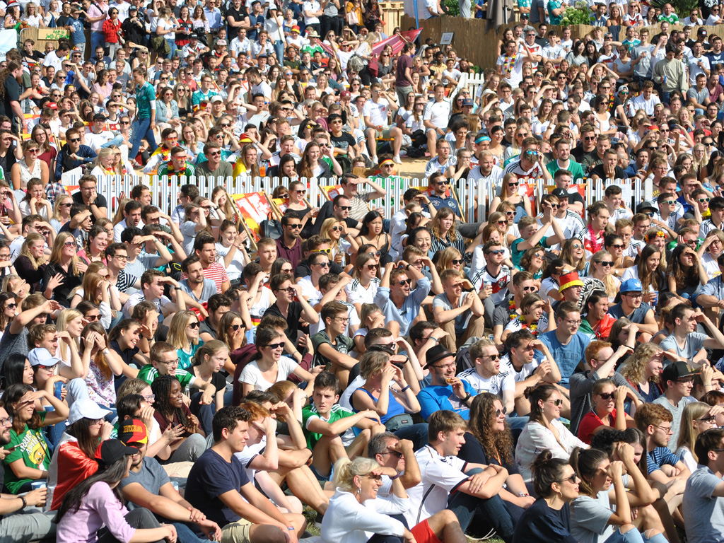 Hunderte Menschen sitzen beim Public Viewing am Unistrand