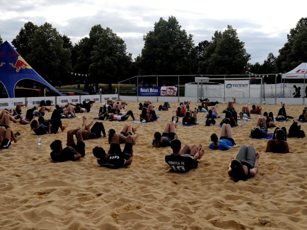 Zwei Dutzend Personen machen beim Morgensport am Unistrand Sit-ups