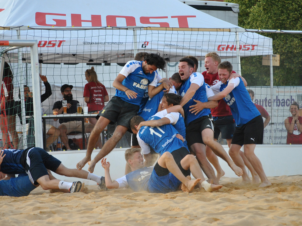 Die Gewinner des Beachsoccer-Turniers machen einen Sauhaufen im Sand
