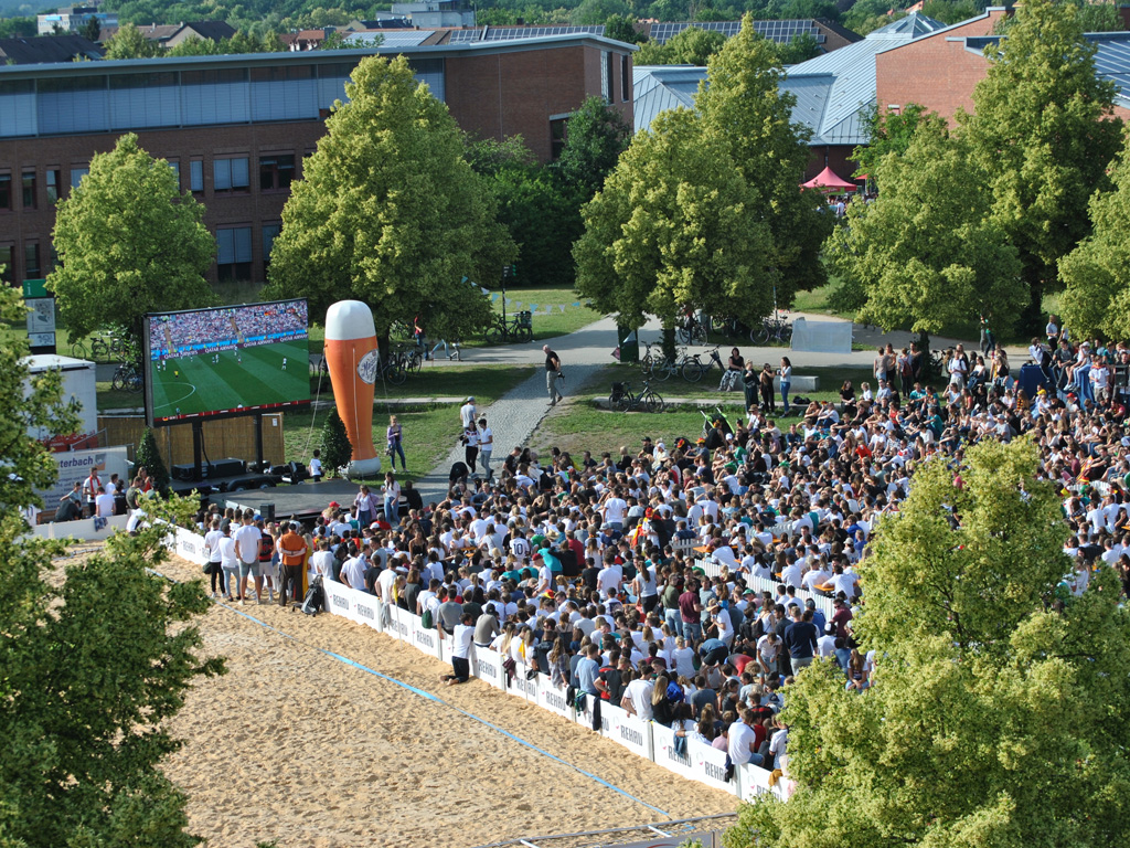 Hunderte Menschen verfolgen ein Fußball-Spiel beim Public Viewing am Unistrand