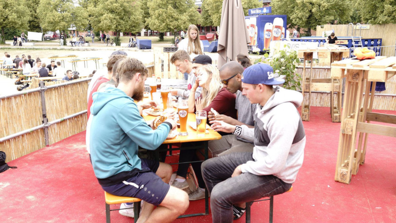 Eine besetzte Bierbank mit Menschen, die ein Weißwurstfrühstück essen